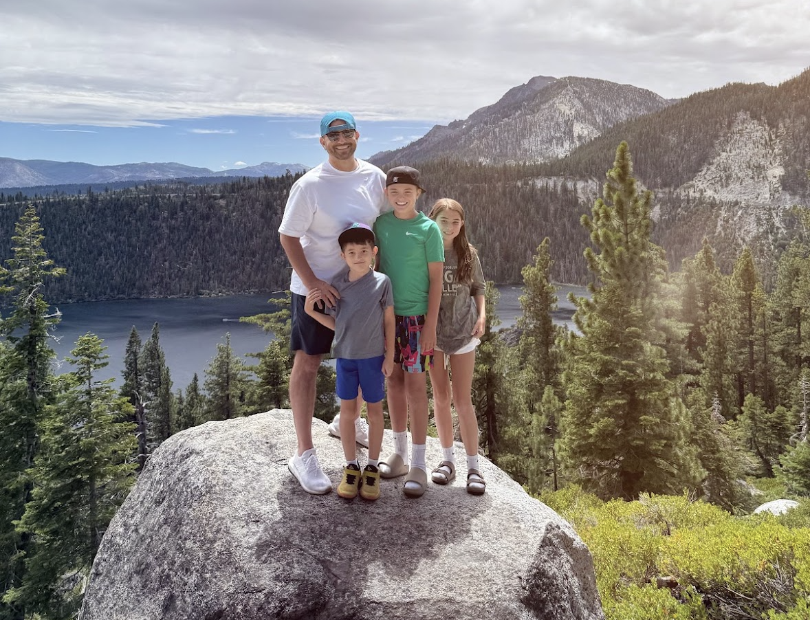 Scott Salkin and his three kids standing on a granite boulder above Lake Tahoe